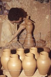 Image du Maroc Professionnelle de  Comme Safi est le chef-lieu de la poterie céramique marocaine, c’est à l’intérieur de son atelier que l’artisan tourneur travaille l'argile brute puis le transforme ainsi dans sa forme, souvent il s'agit d'objets de forme essentielle destinés à l'usage domestique. Quand l’objet est façonné selon le besoin une petit lame est utilisé pour donner à l'objet un aspect lisse. Souvent les artisans ont recours à leur dextérité afin de fignoler la décoration à Safi Vendredi 29 Août 1997.(Photo / Abdeljalil Bounhar)